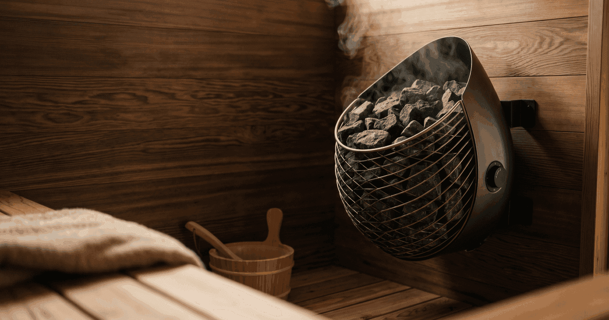 HUUM Drop teardrop sauna heater wall-mounted in a modern home sauna, showing the stone-pack basket.